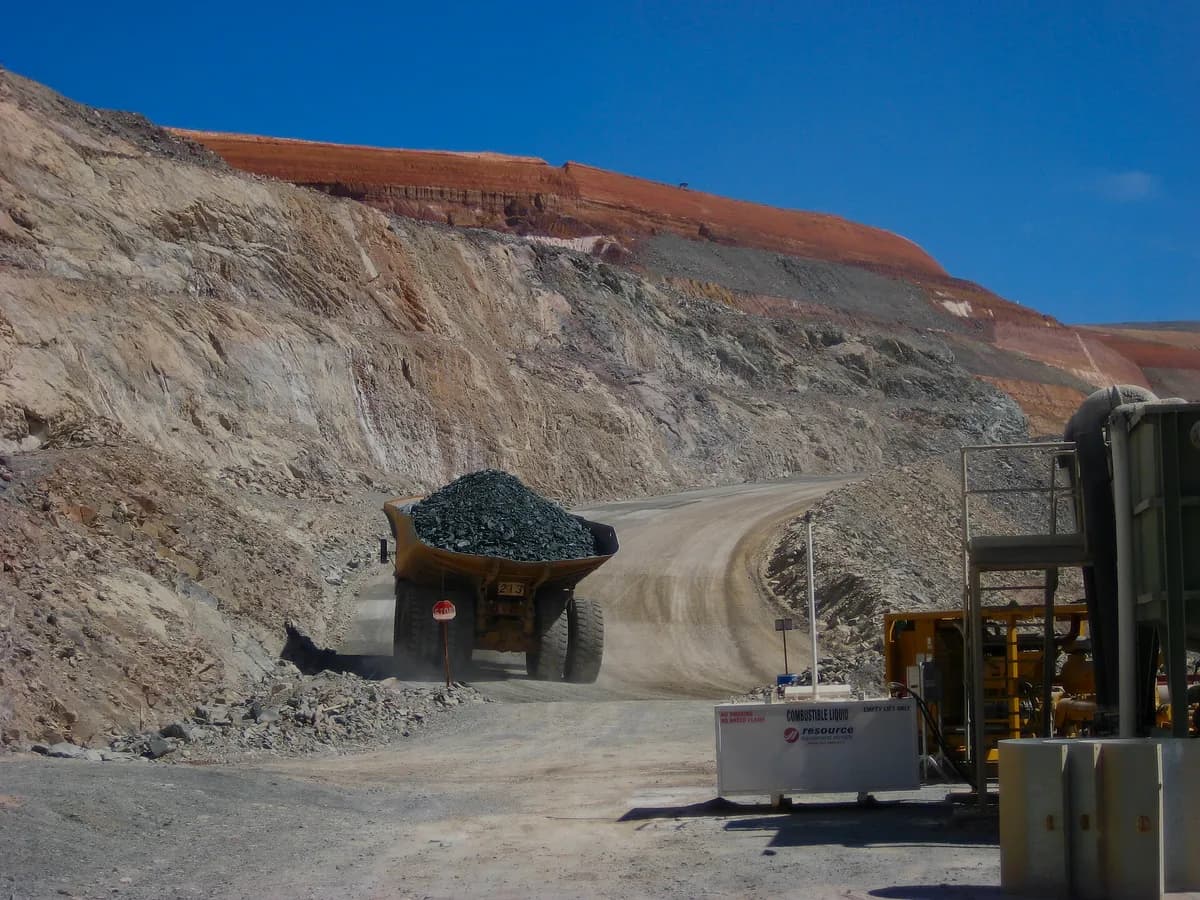 Open-pit gold mine terraces at golden hour — BursaMineral.com premium domain